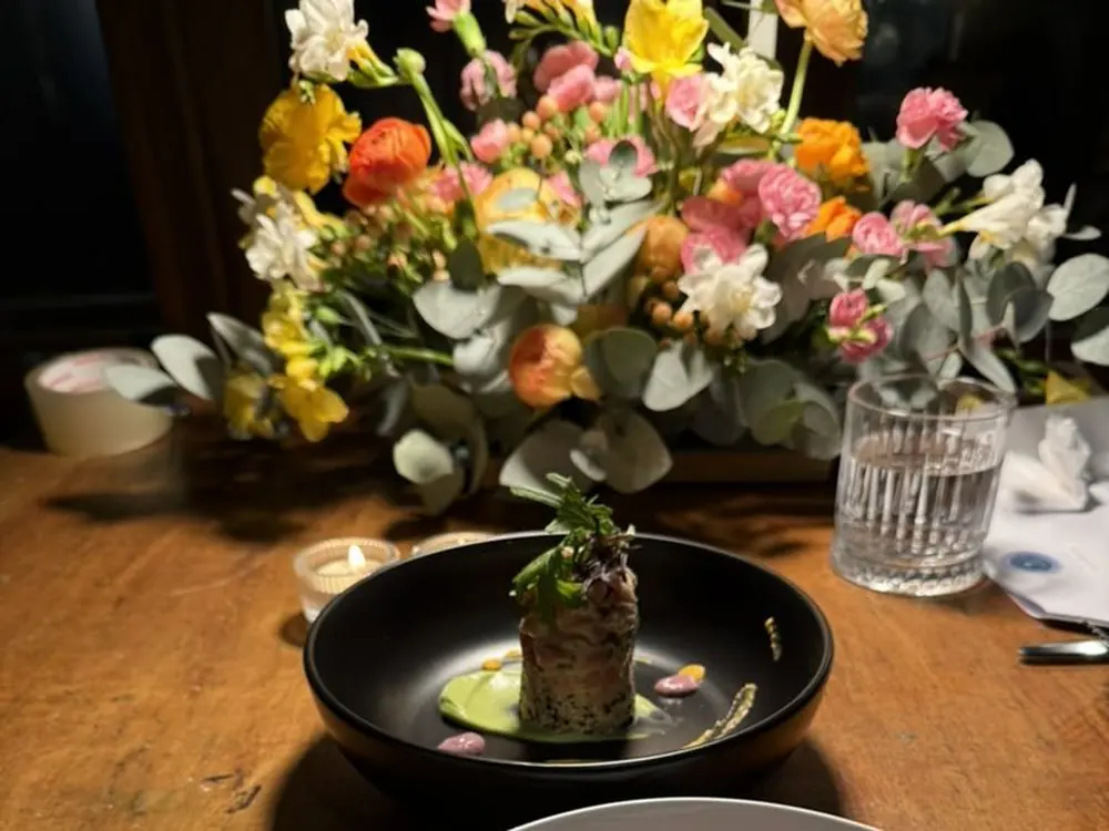 Plato de autor servido en una mesa con flores durante un evento