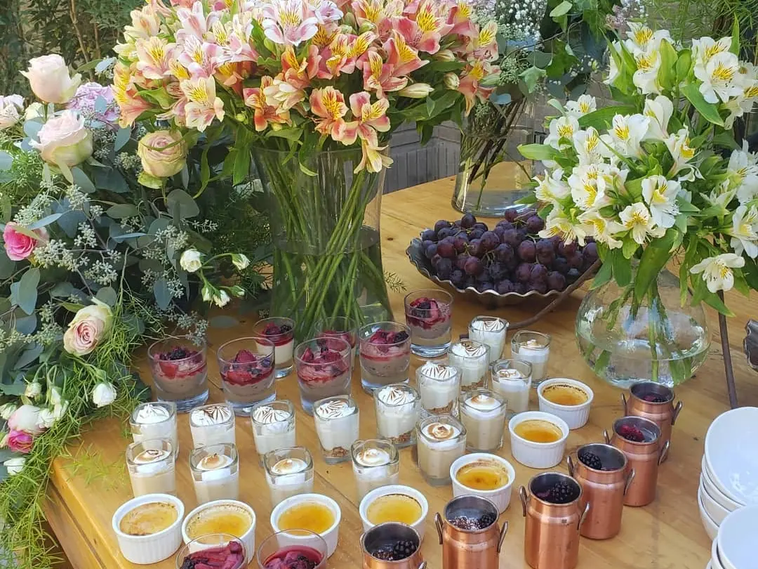 Mesa de postres individuales montada con flores frescas para una pausa