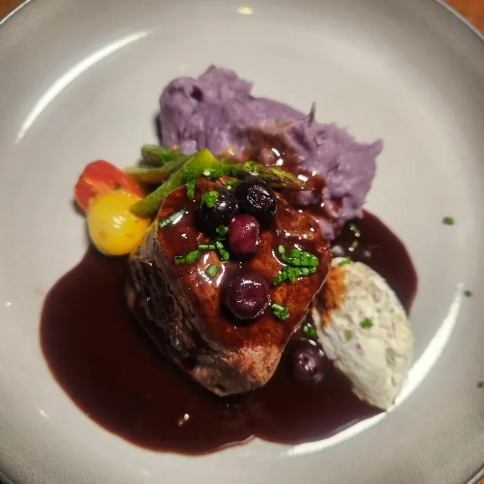 Carne con puré morado y berries en salsa de vino tinto