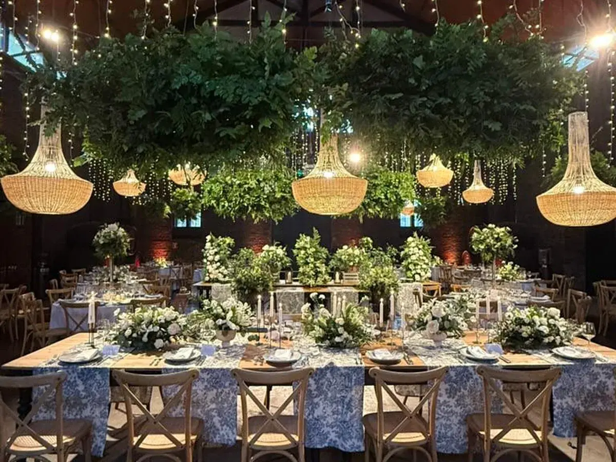 Salón montado con follaje colgante, cortina de luces y mesas largas