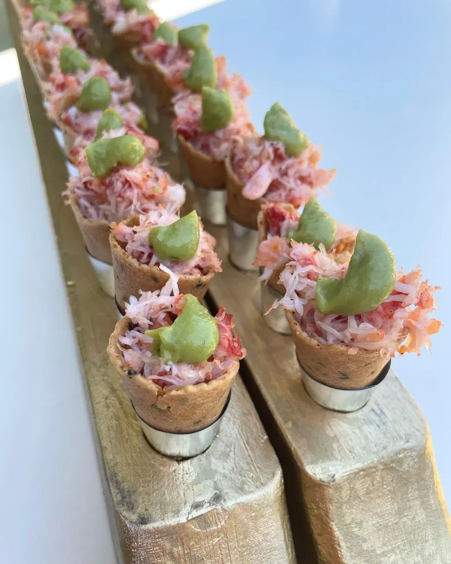 Canapés individuales de jaiba montados en una tabla de madera
